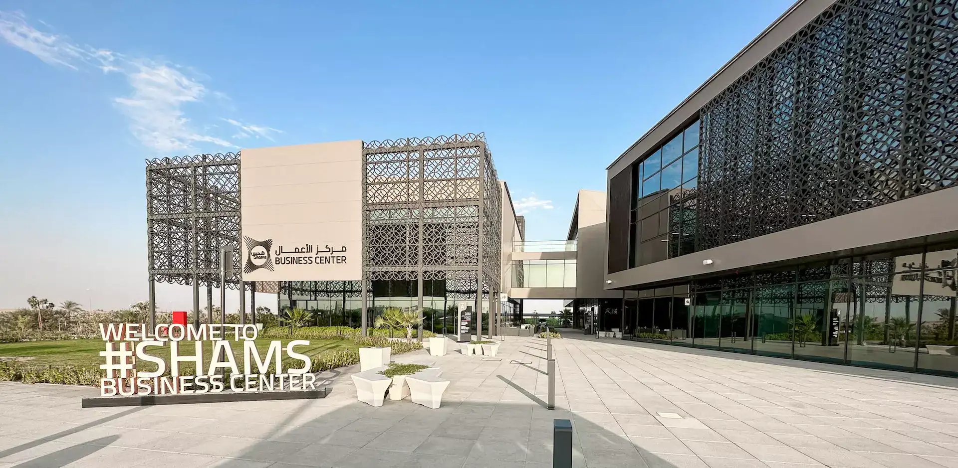 Shams Business Center campus in Sharjah — Welcome to #SHAMS sign in front of the mashrabiya-clad buildings
